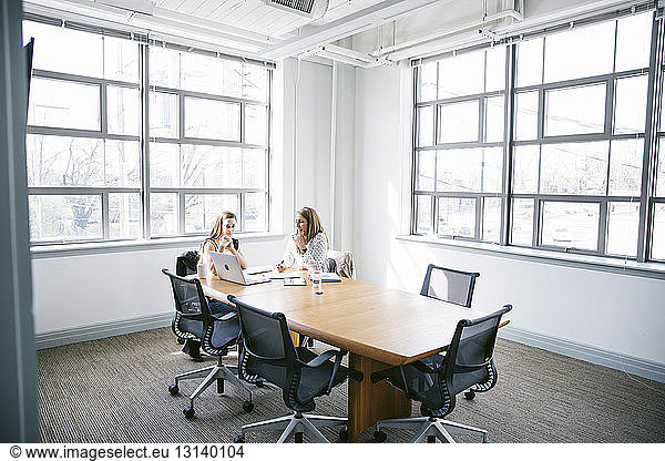 Female colleagues discussing in board room at office