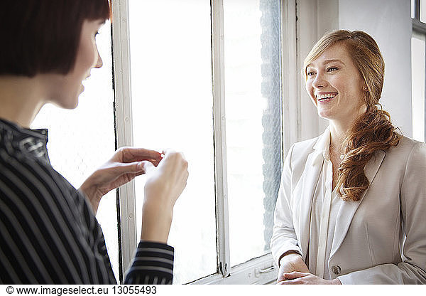 Female colleagues having discussion by window in office
