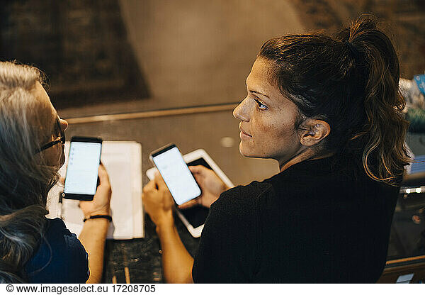 Female colleagues using smart phone in retail store