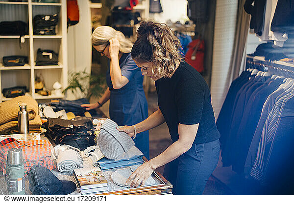 Female coworkers arranging clothes in retail store