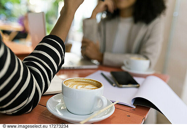 Female coworkers with coffee drink on table in cafe