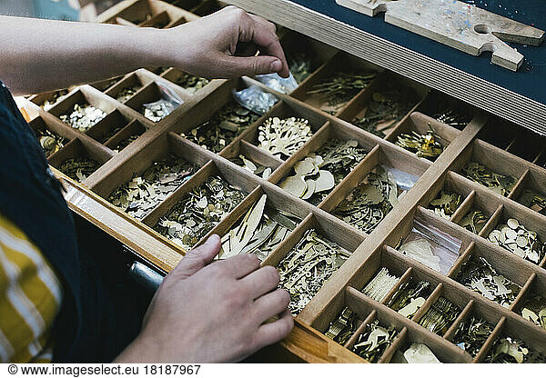 Female craftsperson opening drawer with jewelry making materials