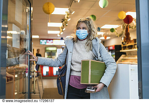 Female customer carrying package while leaving store during COVID-19