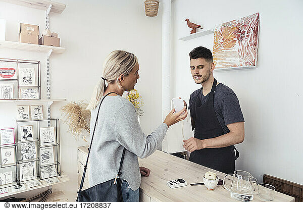 Female customer showing smart phone to male entrepreneur at store