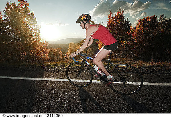 Female cyclist on road at sunset