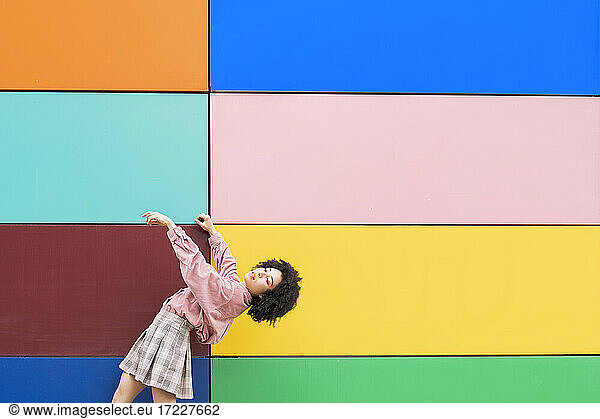 Female dancer bending over backwards while standing by multi colored wall