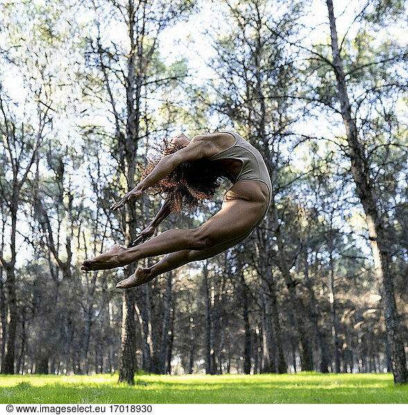Female dancer jumping during performance in middle of forest