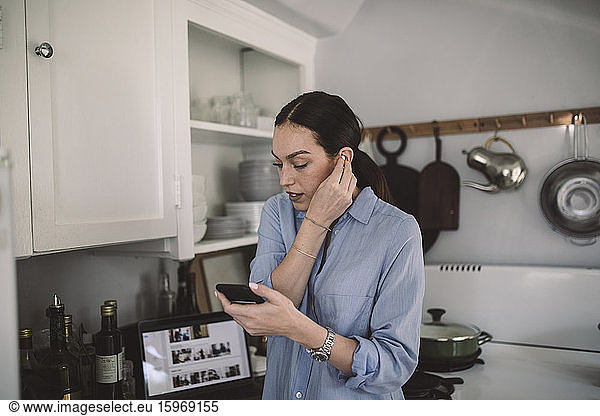 Female design professional wearing in-ear headphones at home office