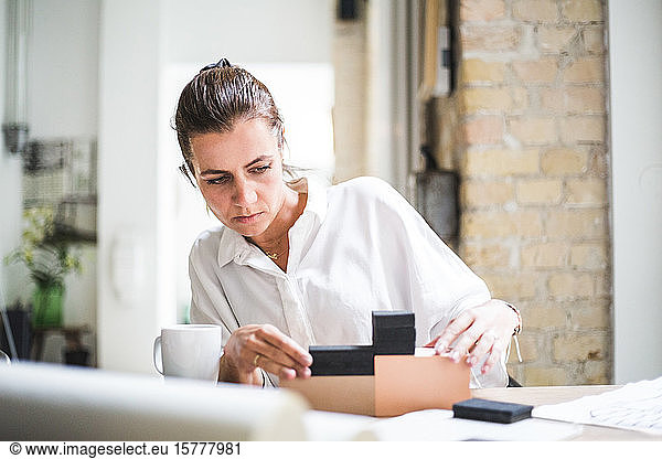 Female design professional working with boxes while sitting at home office