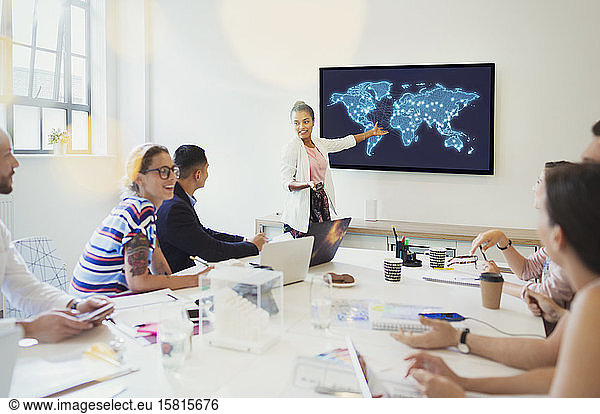 Female designer at television screen leading conference room meeting