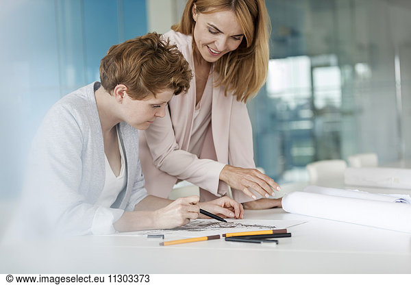 Female designers reviewing sketch drawings in conference room meeting