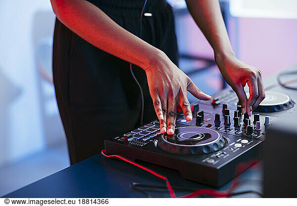 Female Dj operating sound mixer at home