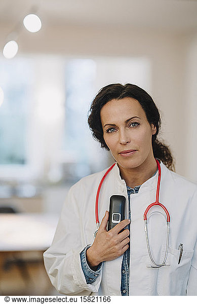Female doctoe standing in hosptal  holding telephone and stethoscope
