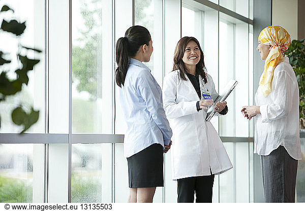 Female doctor and nurse discussing with mature patient in hospital