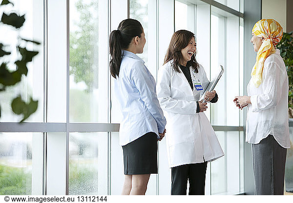 Female Doctor and nurse talking to mature patient in hospital