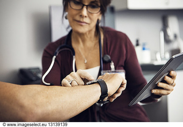 Female doctor checking time on patient's wristwatch in clinic