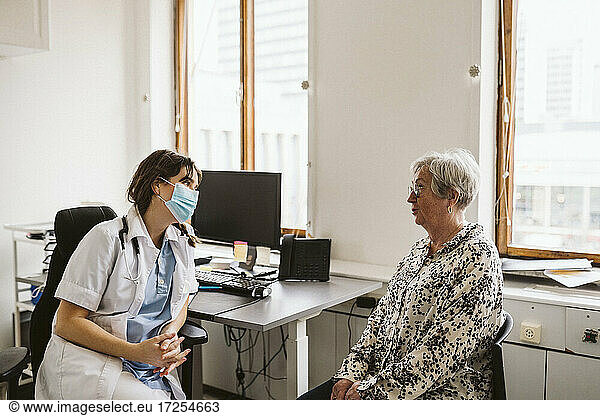 Female doctor consulting senior patient during COVID-19