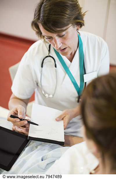 Female doctor discussing notes with patient in hospital ward