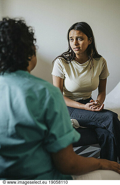 Female doctor discussing with young woman in clinic