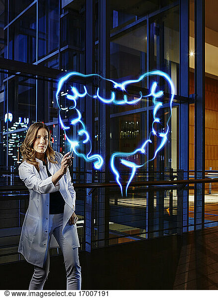 Female doctor examining large intestine with light painting at hospital