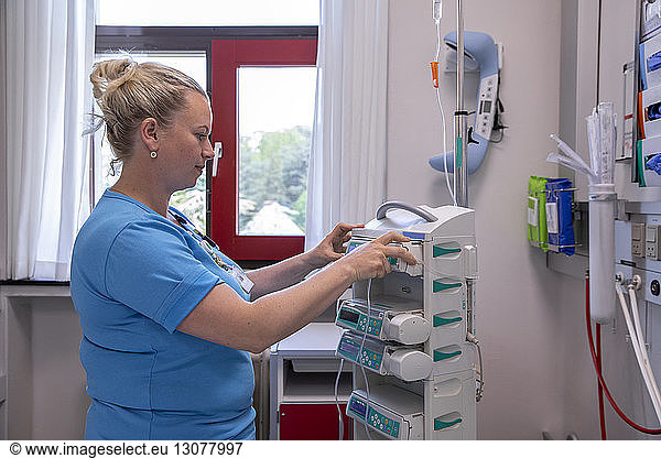 Female doctor examining medical equipment while standing in hospital