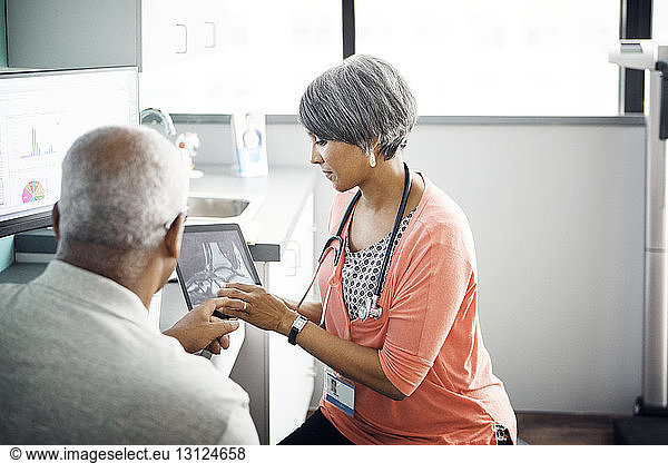 Female doctor explaining x-ray to patient on tablet computer in clinic