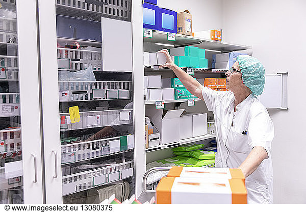 Female doctor looking medicine boxes in storage room at hospital