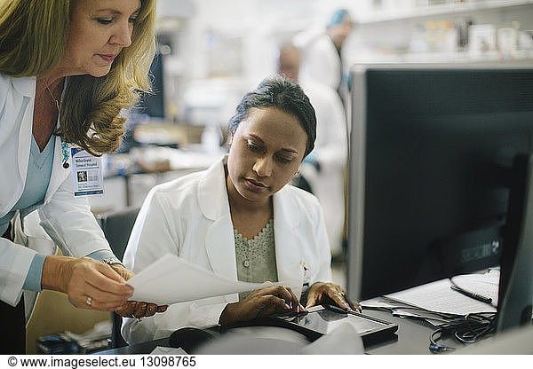Female doctor showing reports to coworker in medical room