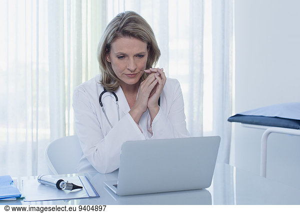 Female doctor sitting at desk with laptop in office