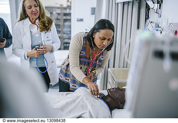 Female doctor training coworkers while examining mannequin in medical school
