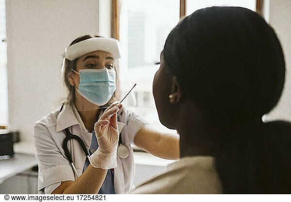 Female doctor wearing protective mask and face shield doing patient's medical test