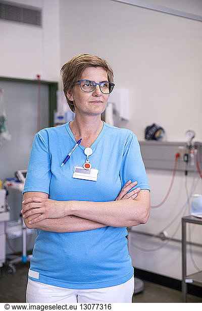 Female doctor with arms crossed looking away while standing in hospital