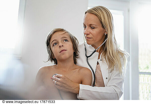 Female doctor with stethoscope examining boy