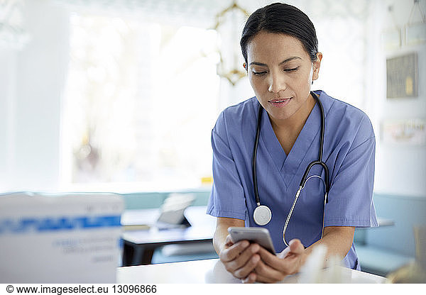 Female doctor with stethoscope using smart phone while working in hospital