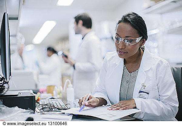Female doctor working at desk with coworkers in background