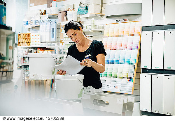 Female employee reading document at hardware store