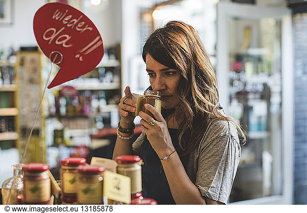 Female employee smelling food in jar at deli