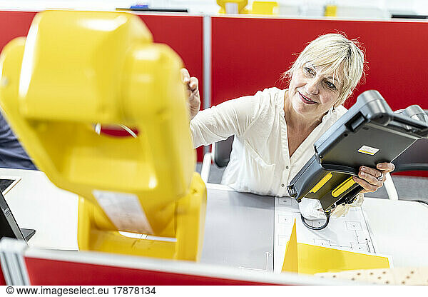 Female engineer working at industrial robot using digital control