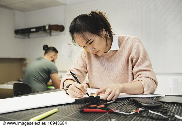 Female engineer working on paper at table in workshop