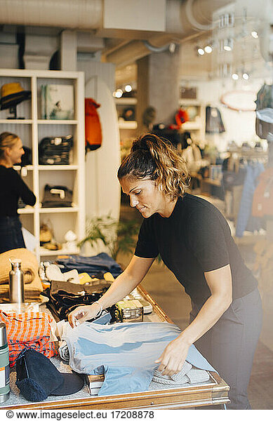 Female entrepreneur arranging clothes at store