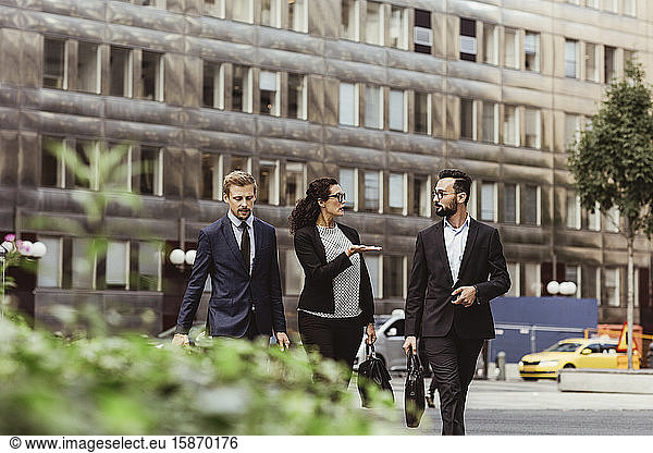 Female entrepreneur discussing business strategy with male colleagues while walking outdoors