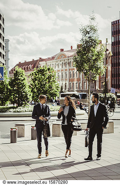 Female entrepreneur discussing strategy with male colleagues while walking outdoors