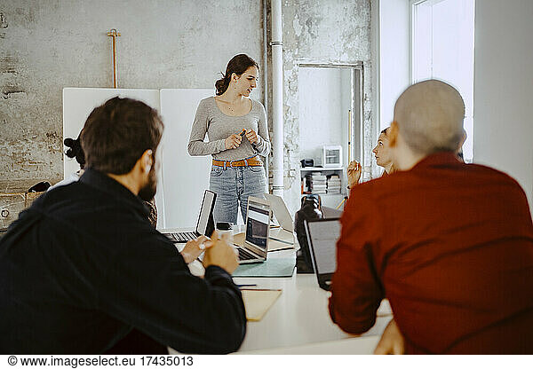 Female entrepreneur discussing with colleagues in startup company