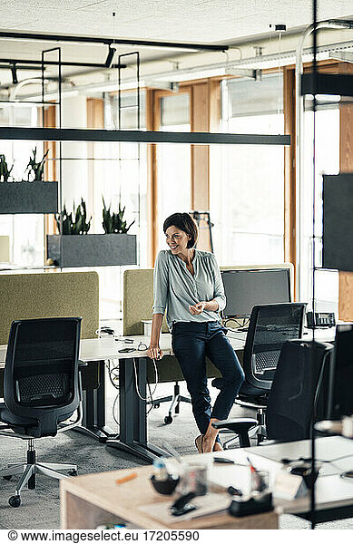 Female entrepreneur leaning on desk in office