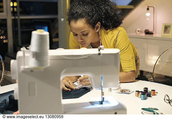 Female entrepreneur measuring jeans on table in office