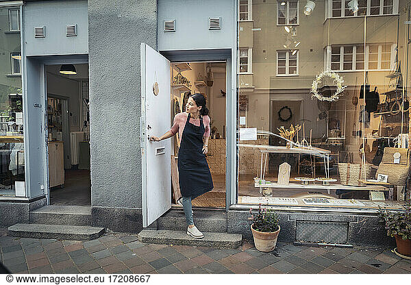 Female entrepreneur peeking out while standing at doorway of design studio