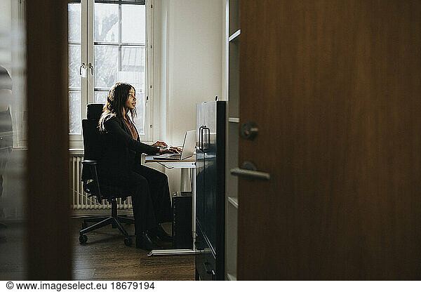 Female entrepreneur sitting on chair and working at office