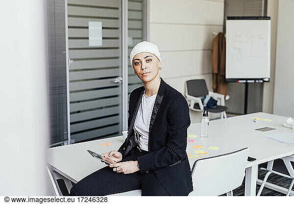 Female entrepreneur sitting with digital tablet on table in office