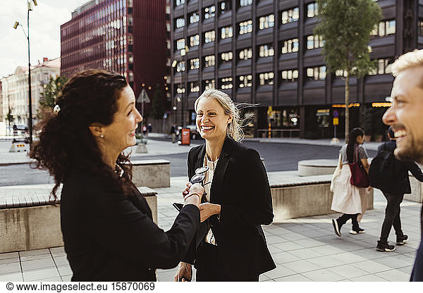 Female entrepreneur smiling with coworkers while standing outdoors