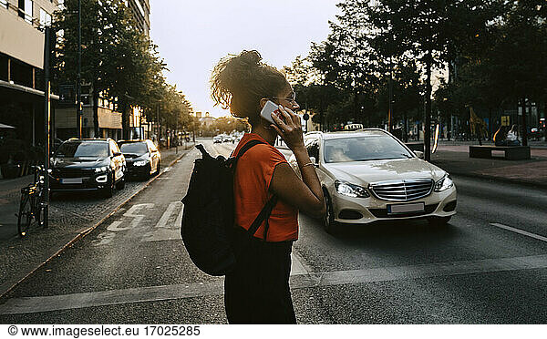Female entrepreneur talking on smart phone while crossing street in city